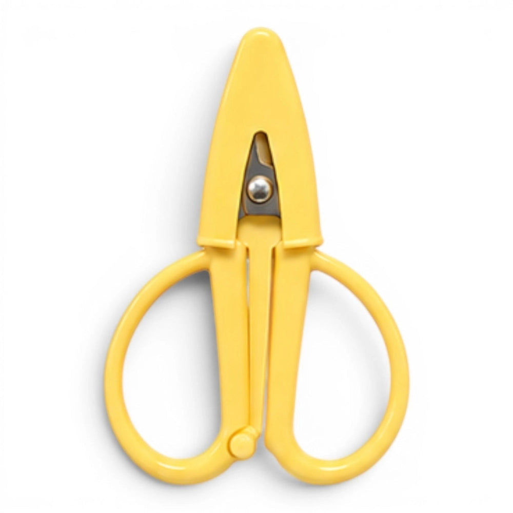 A small butter yellow pair of scissors with a matching point protector on a white background