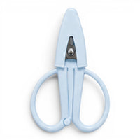A small baby blue pair of scissors with a matching point protector on a white background