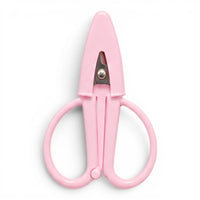 A small baby pink pair of scissors with a matching point protector on a white background