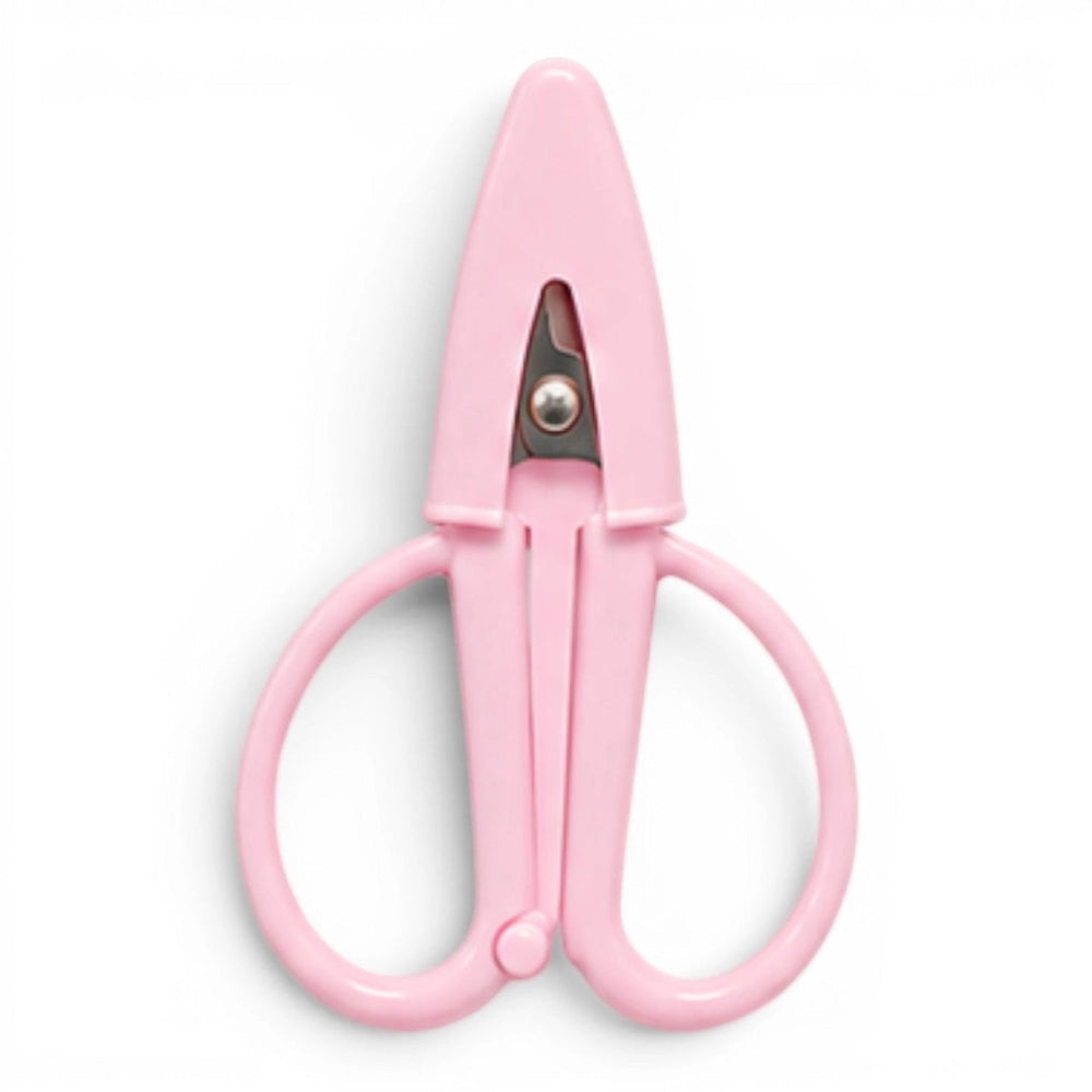 A small baby pink pair of scissors with a matching point protector on a white background