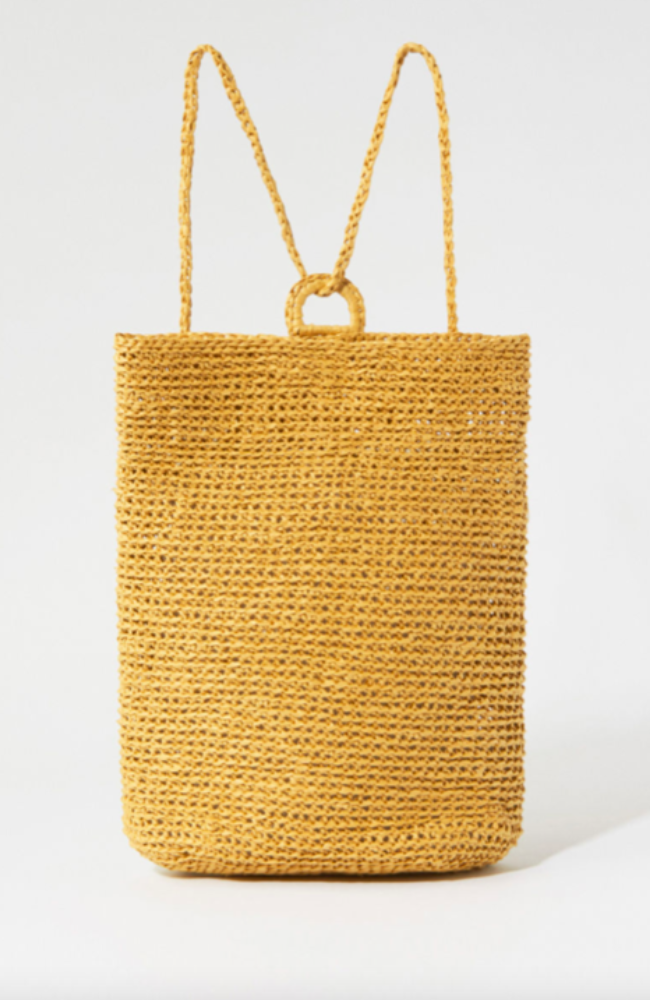 Yellow straw crocheted backpack with loop closure on a white background.