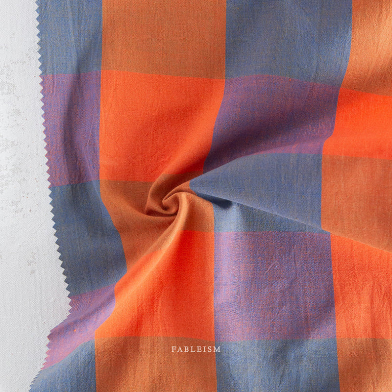 Checkered fabric with orange and blue pattern on a white background, featuring the brand 'Fableism'.