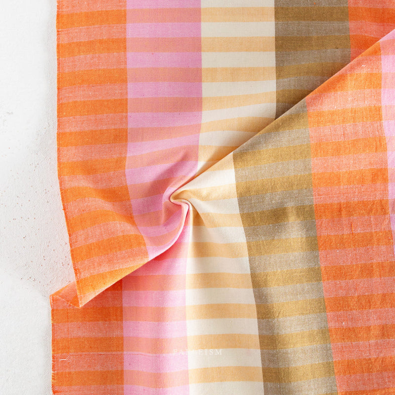 Fabric with orange, pink, and beige plaid pattern on a light background