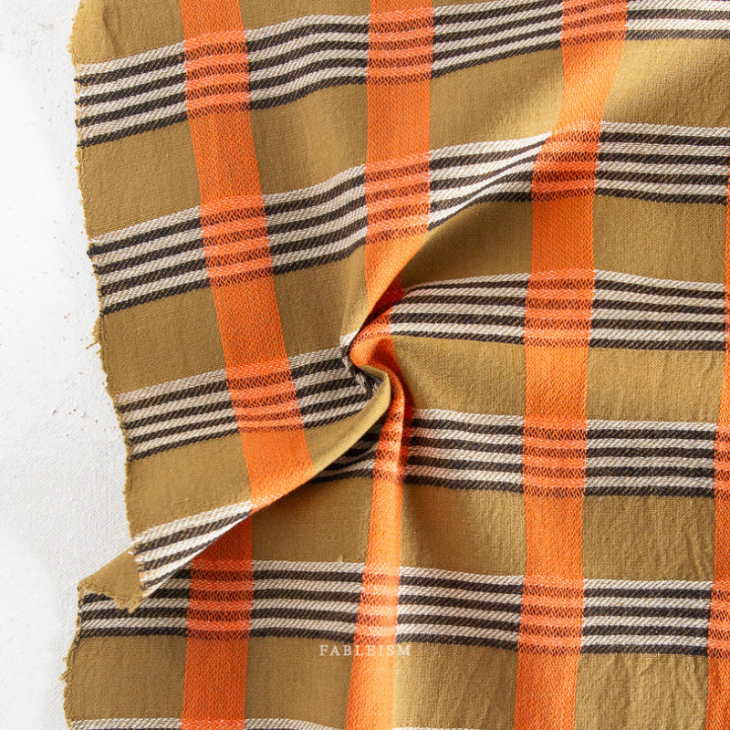 Plaid fabric with orange, brown, and black stripes on a white background