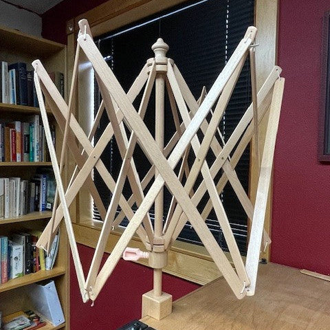 wooden yarn swift with red wall and bookshelf in the background