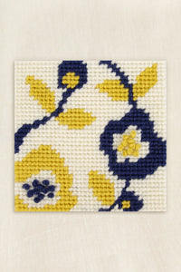 Needlepointed floral design with yellow and blue flowers on a white background