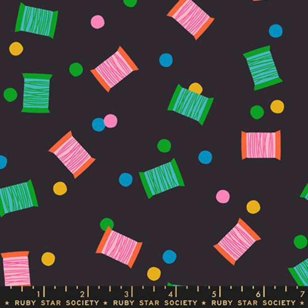 Colorful thread spools and polka dots pattern on a black background with a ruler  with the Ruby Star Society label.