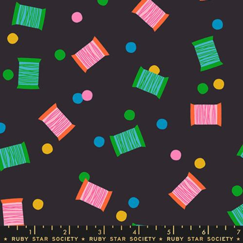 Colorful thread spools and polka dots pattern on a black background with a ruler  with the Ruby Star Society label.
