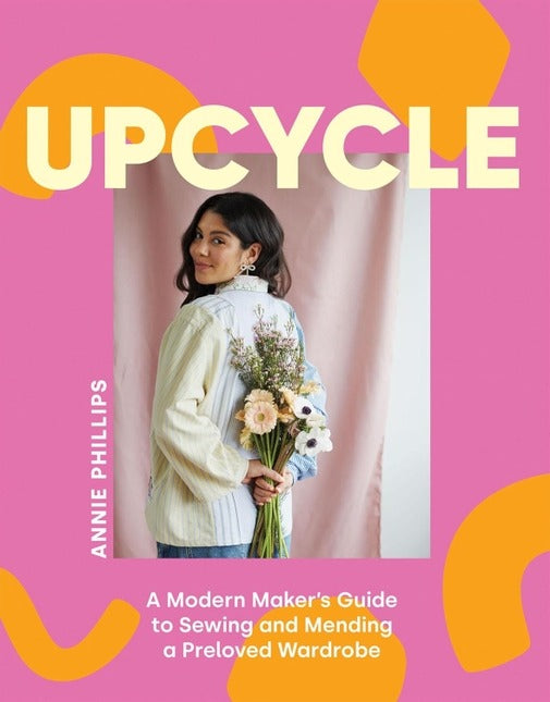 Book cover of 'Upcycle' by Annie Phillips with a person holding flowers against a pink background.