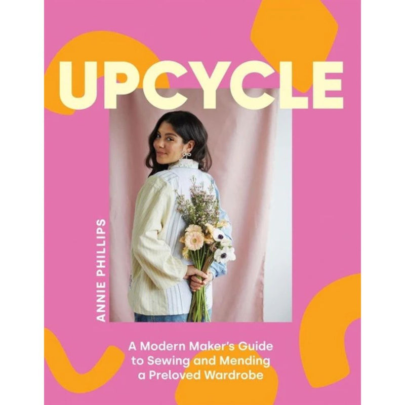 Book cover of 'Upcycle' by Annie Phillips with a person holding flowers against a pink background.