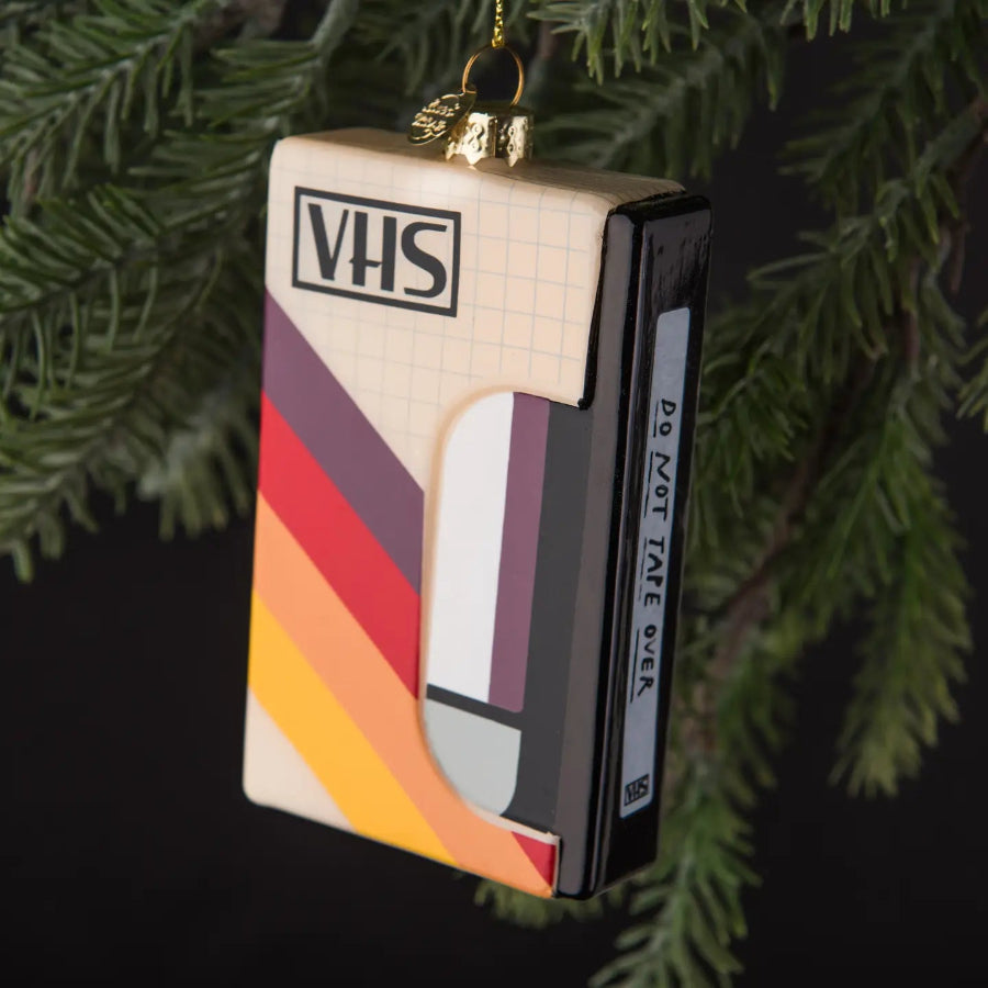 VHS tape ornament with colorful stripes on a green leafy background