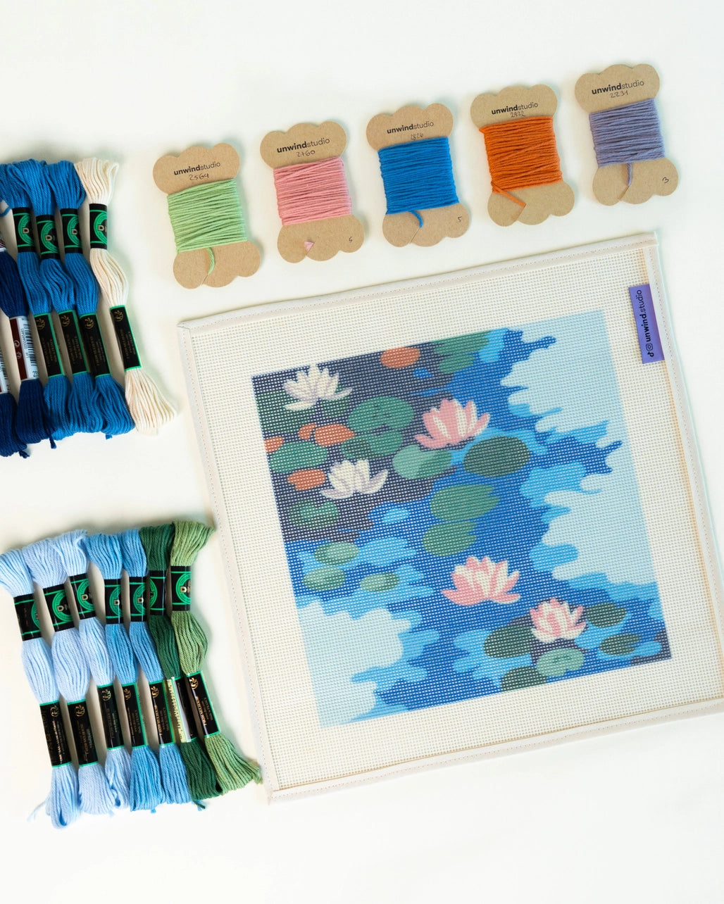 Needlepoint kit supplies including a canvas and skeins of thread on a white background