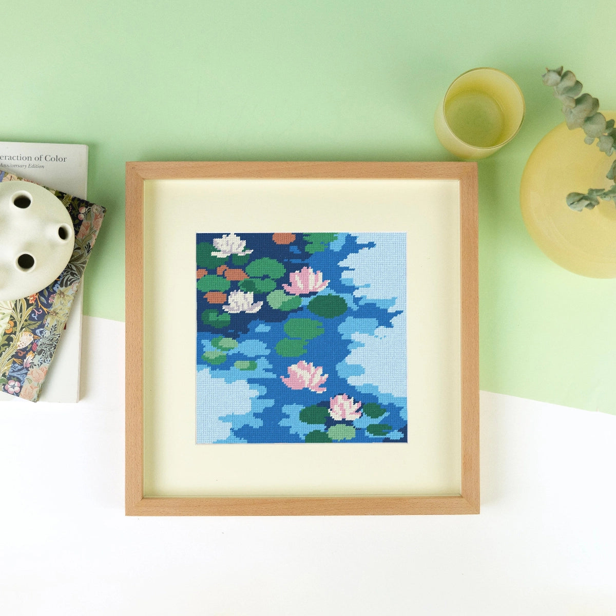 Framed needlepoint artwork with a floral design on a white and green background