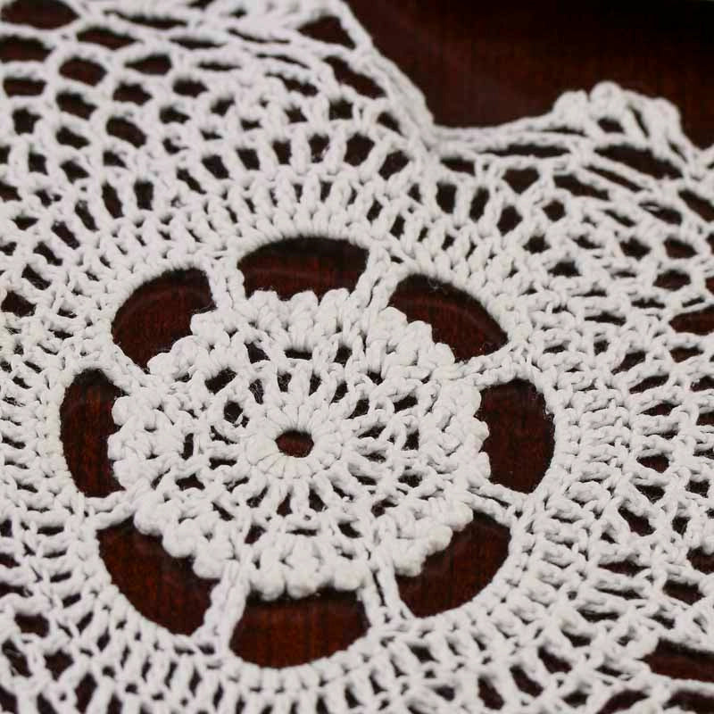 Close-up of a white crocheted doily on a dark surface