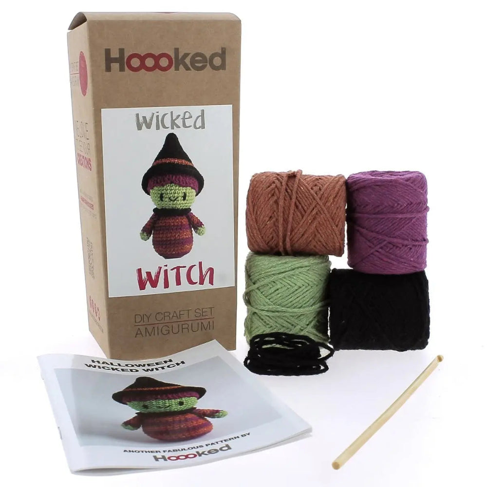 The contents of the wicked witch kit, including four colors of yarn, a crochet hook and an instruction booklet, all pictured against a white background.