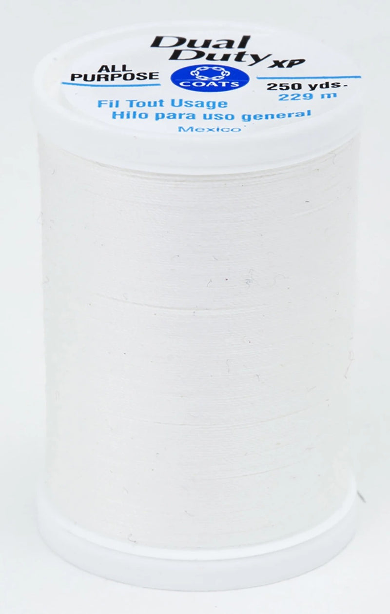 A spool of white Dual Duty XP sewing thread with a white label featuring blue and black text, set against a plain white background.