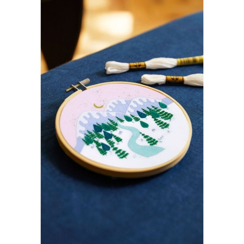 Embroidery hoop with a nature-themed design on a blue fabric background