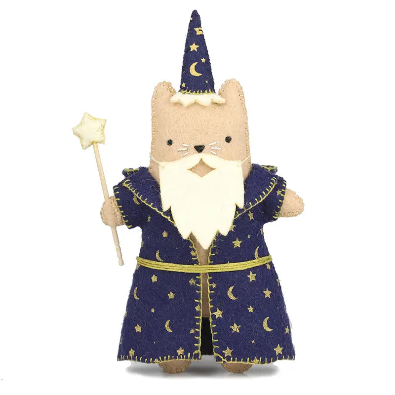 A felt cat toy dressed in a wizard costume, featuring a beige body, a blue robe and hat with gold moons and starts, and a wand with a star on top, set against a plain white background