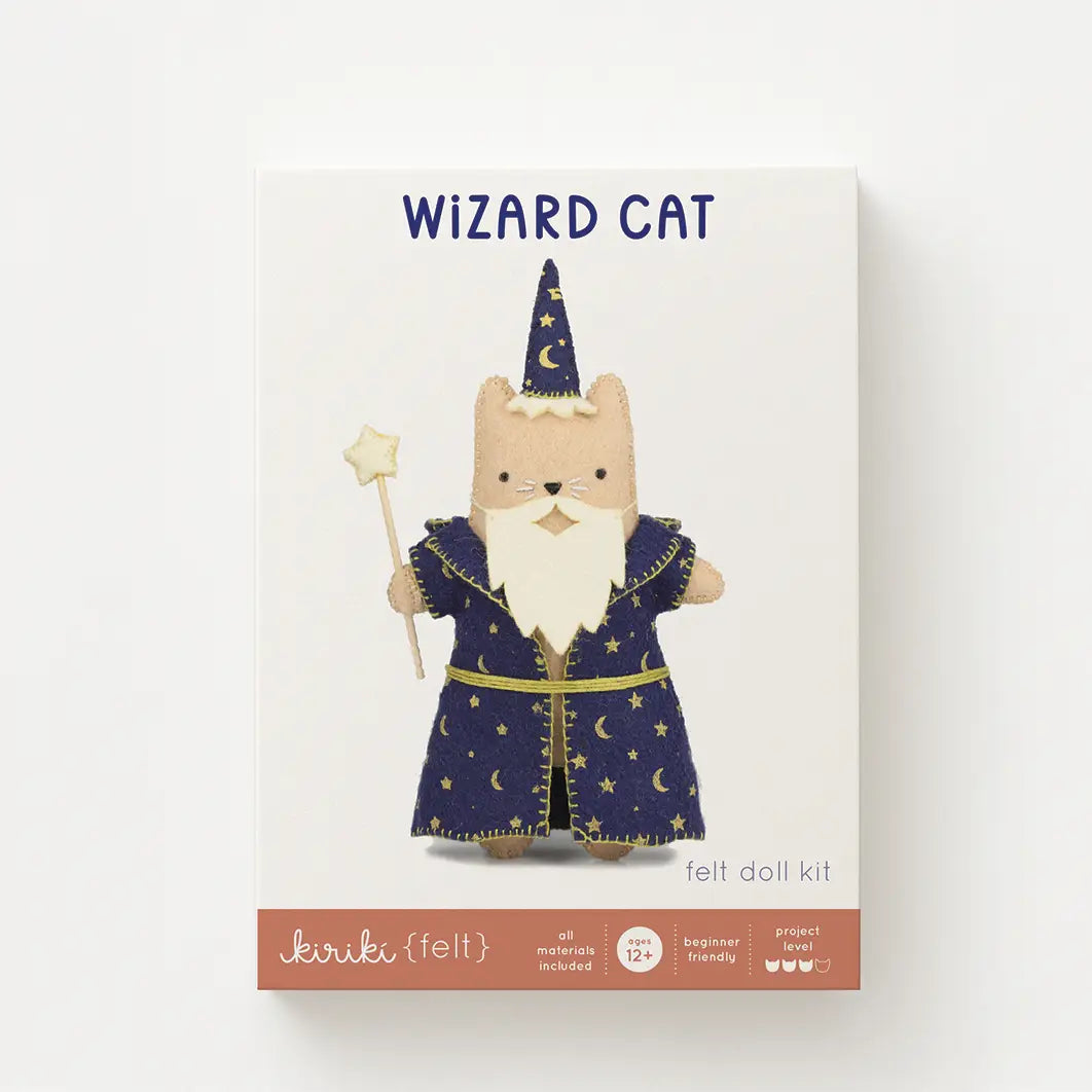 Front of a felt doll kit box labeled 'WIZARD CAT felt doll kit' with an illustration of a beige cat wearing a blue wizard robe and hat, on a white background.