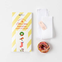 Cotton Clara bookmark cross-stitch kit with packaging, white fabric, and colorful thread on a white background