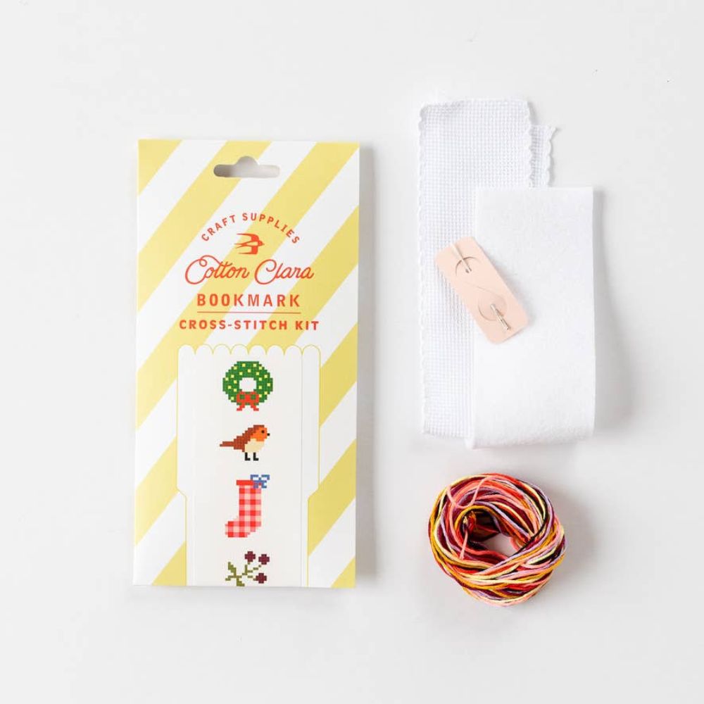 Cotton Clara bookmark cross-stitch kit with packaging, white fabric, and colorful thread on a white background