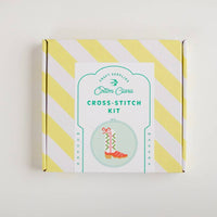 Cotton Clara cross-stitch kit packaging with yellow and white striped design on a light gray background