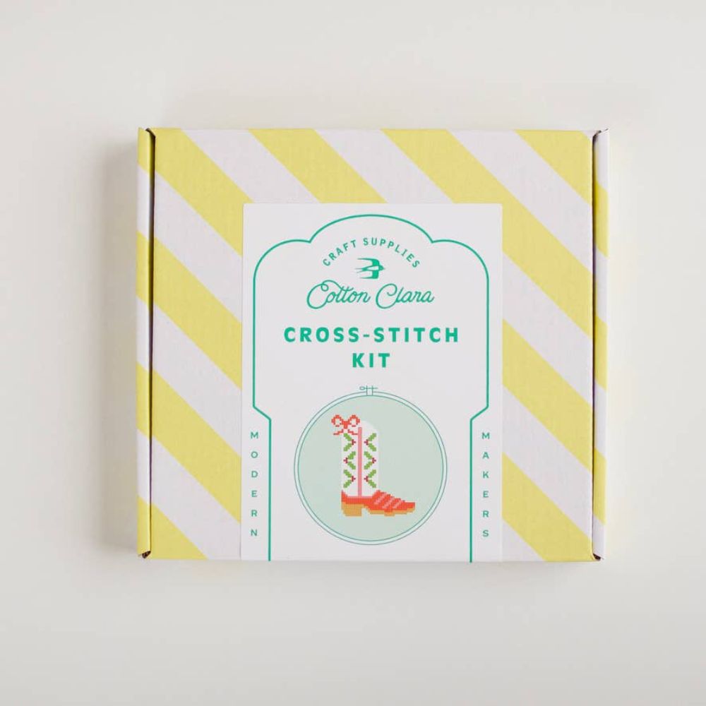 Cotton Clara cross-stitch kit packaging with yellow and white striped design on a light gray background