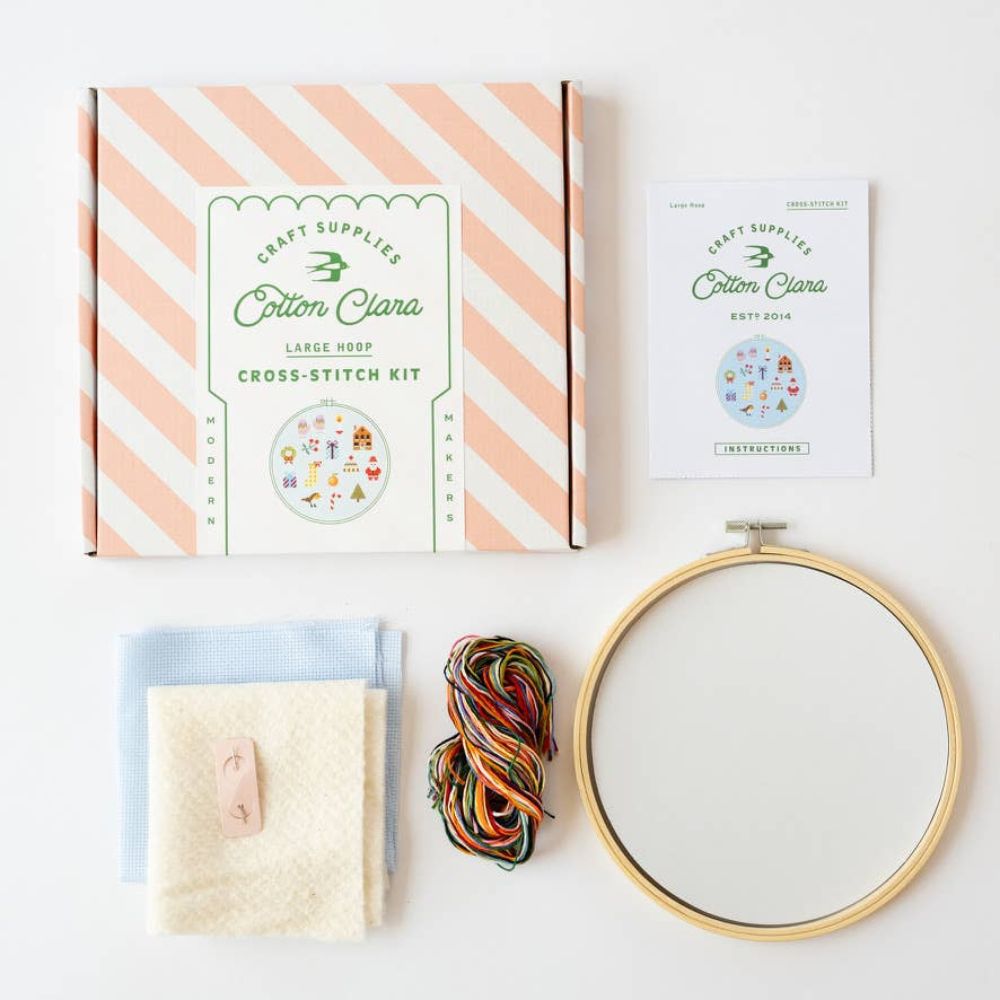 Cross-stitch kit with hoop, yarn, and instructions on a white background