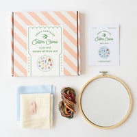 Cross-stitch kit with hoop, yarn, and instructions on a white background